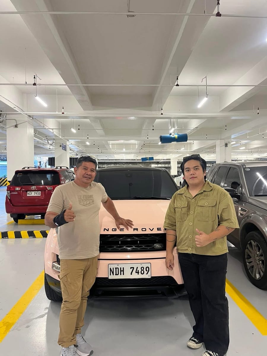 Buyer and seller giving a thumbs-up beside a Range Rover Evoque at handoff